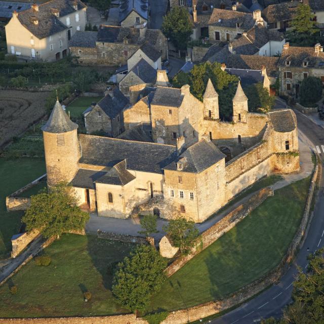 Vue aérienne du château d'Onet-le-Château : son mur d'enceinte et ses tourelles, à côté du village