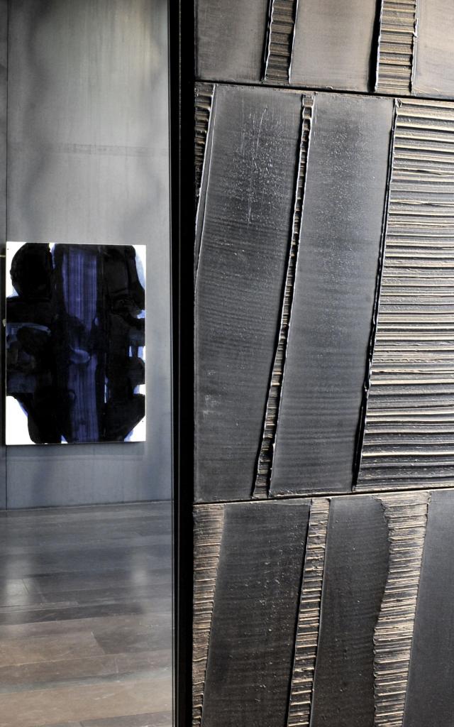 Outrenoir au premier plan, derrière une personne qui admire une autre toile avec des bleus, au musée Soulages à Rodez