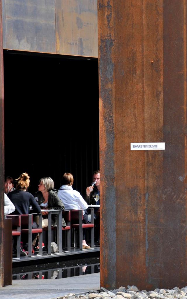 Personnes en train de déjeuner en terrasse au Café Bras, vues depuis l'entrée du restaurant