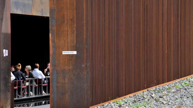 Personnes en train de déjeuner en terrasse au Café Bras, vues depuis l'entrée du restaurant