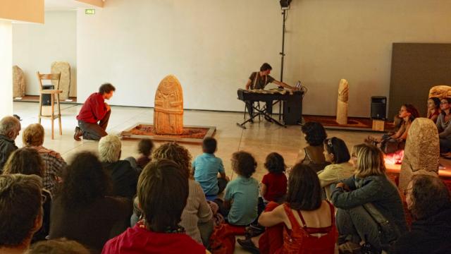 Nombreuses personnes autour d'une statue-menhir, lors d'un atelier au Musée Fenaille de Rodez