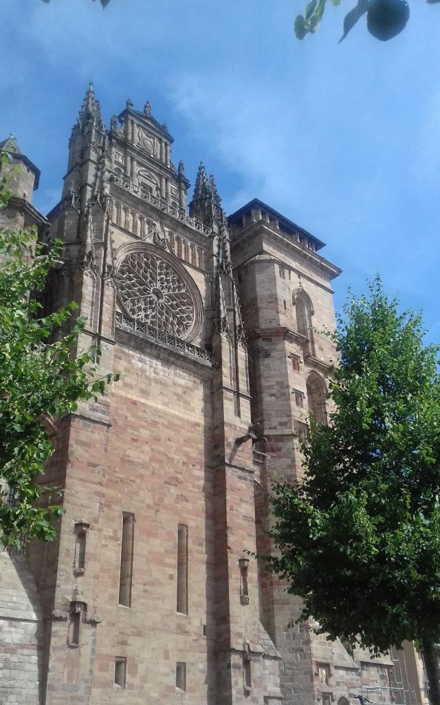 Façade en grès rose de la cathédrale de Rodez avec la rosace entre deux arbres
