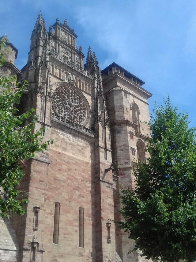 Façade en grès rose de la cathédrale de Rodez avec la rosace entre deux arbres