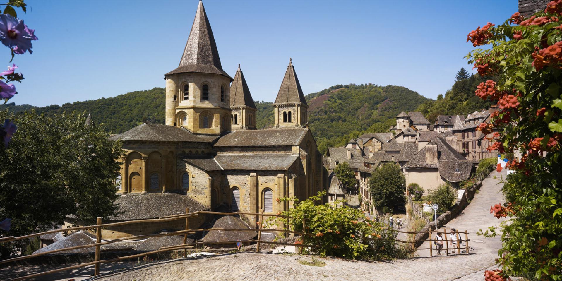 Au bord d'un chemin pavé, abbaye Cistercienne au cœur du village typique de Conques