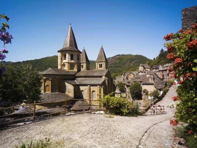 Au bord d'un chemin pavé, abbaye Cistercienne au cœur du village typique de Conques