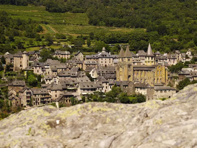 Vue sur le village de Conques et son abbaye, depuis un promontoire en pierre