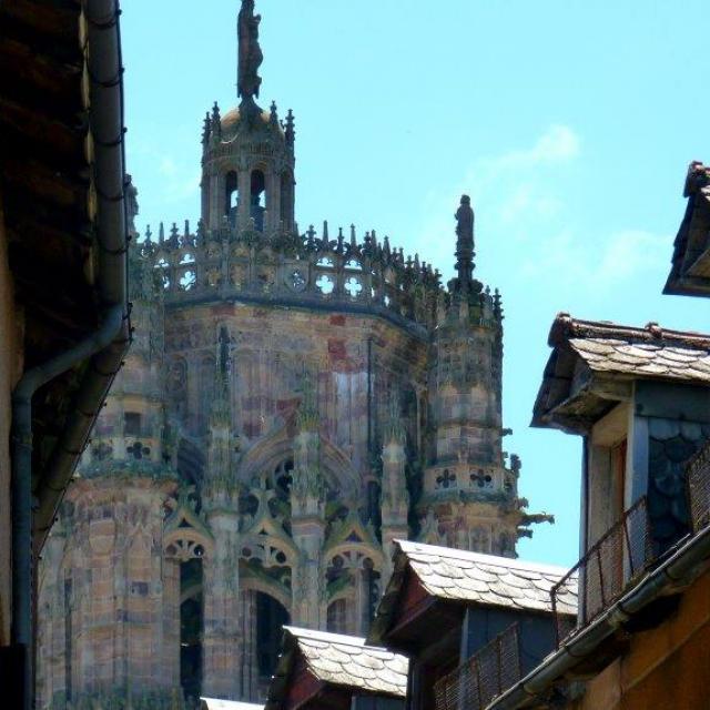 Vue sur le clocher de la cathédrale depuis une ruelle de Rodez, entre une maison à colombages et une maison aux nombreuses fenêtres