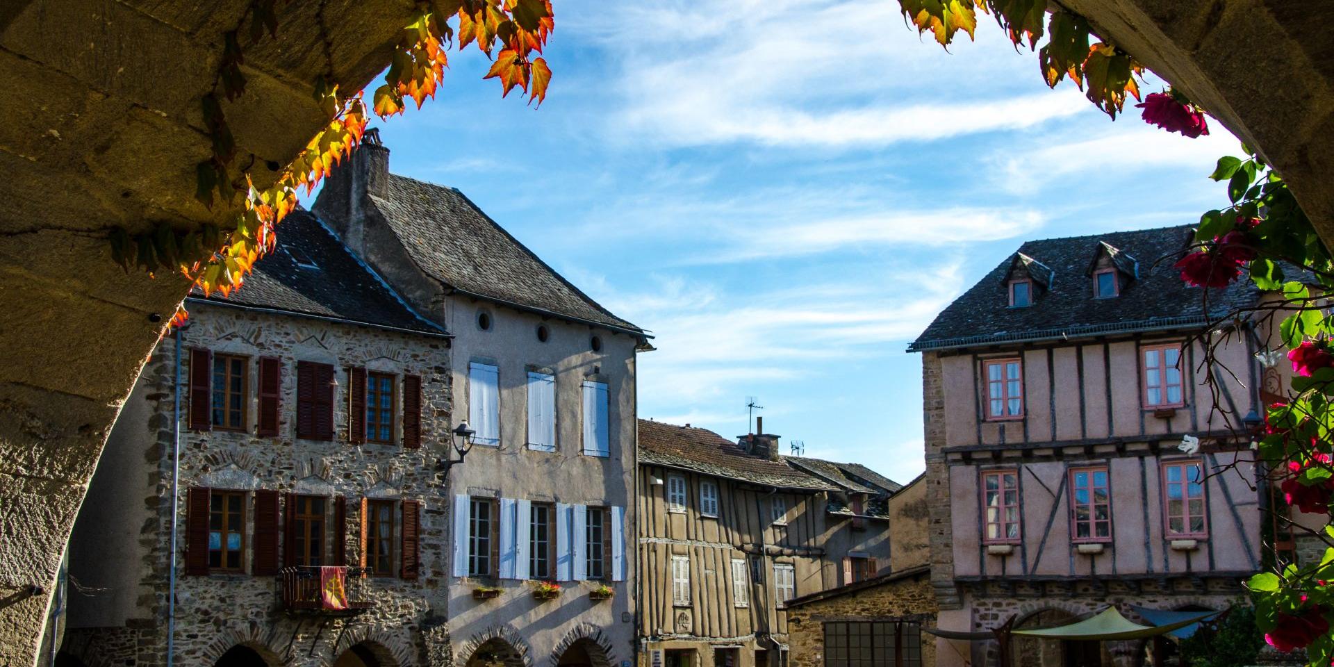 Place de Sauveterre De Rouergue avec ses maisons à colombages, vue en perspectives depuis une des arcades