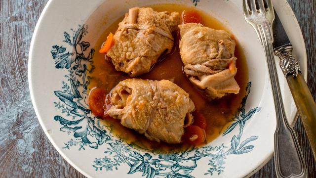 Assiettes de trois tripous dans leur sauce avec des carottes, sur une table en bois avec une fourchette et un couteau