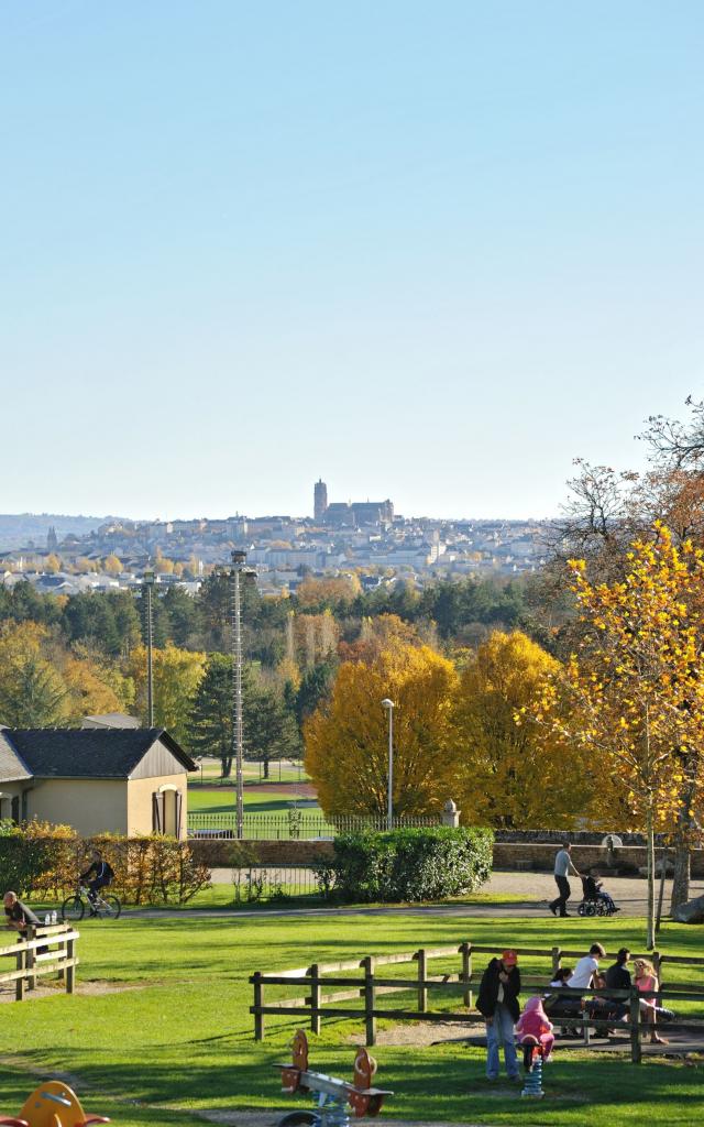 Enfants jouant aux jeux de bois sous les yeux de leurs parents, au parc de Vabre, avec vue sur la cathédrale au loin