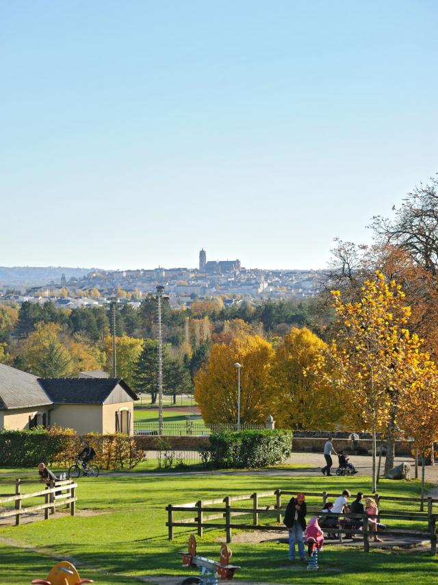 Enfants jouant aux jeux de bois sous les yeux de leurs parents, au parc de Vabre, avec vue sur la cathédrale au loin