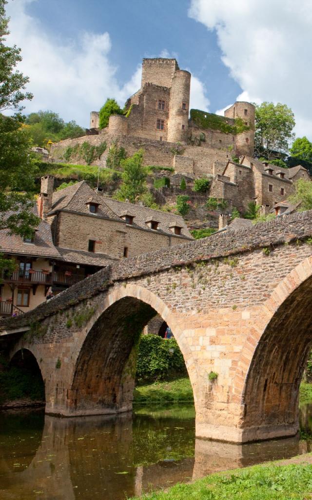 Depuis la rivière Aveyron, vue d'un pont en pierre, les maisons et le château de Belcastel en haut du village