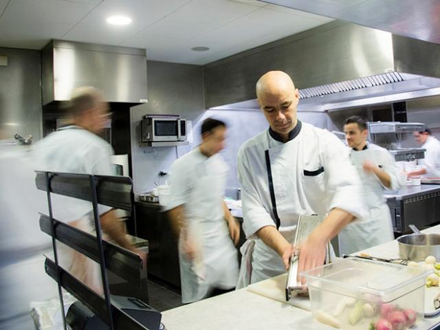 Le Chef Chaillou du Café Bras en cuisine, en train de couper des légumes, au milieu de l'agitation de sa brigade