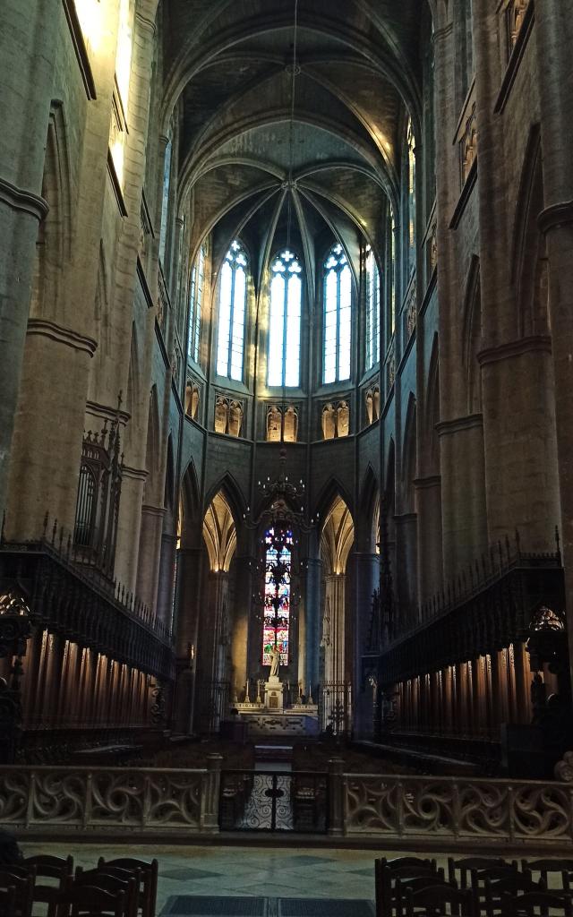 Autel de la cathédrale avec des stalles en bois au milieu de l'allée principale, sous les vitraux gotiques