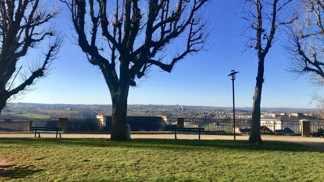 Vue sur Rodez et Olemps depuis le square Fabié où il y a des bancs, une promenade et des arbres nus