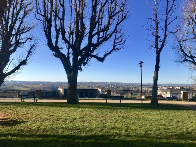 Vue sur Rodez et Olemps depuis le square Fabié où il y a des bancs, une promenade et des arbres nus