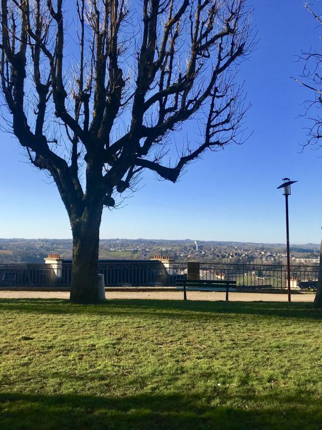 Vue sur Rodez et Olemps depuis le square Fabié où il y a des bancs, une promenade et des arbres nus