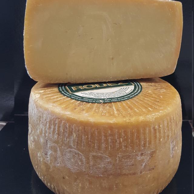 Meule ronde entière de fromage Le Rodez avec son étiquette par-dessus, surmontée d'une demi-meule
