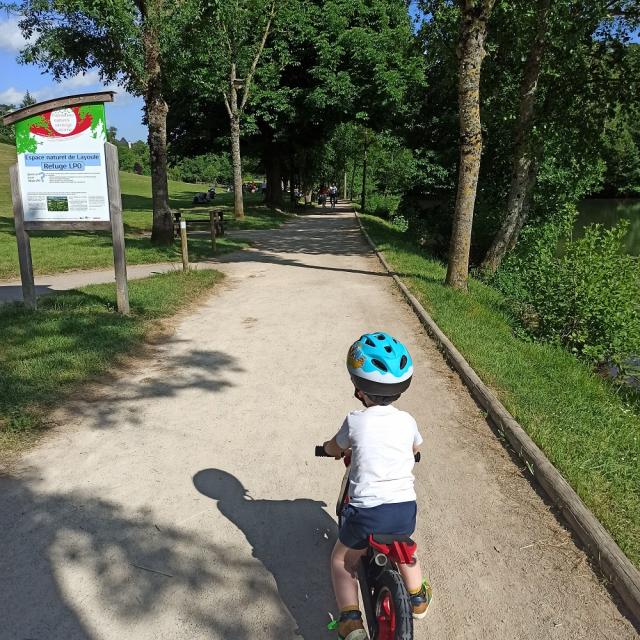 Enfant sur une draisienne sur un chemin à l'entrée du site de Layoule au bord de la rivière Aveyron