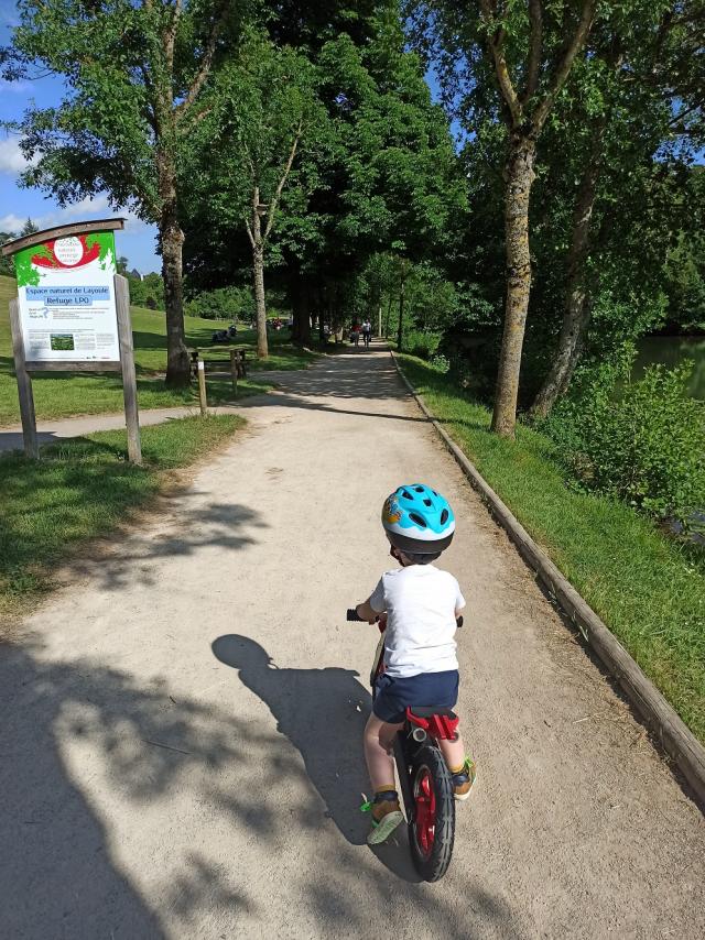 Enfant sur une draisienne sur un chemin à l'entrée du site de Layoule au bord de la rivière Aveyron