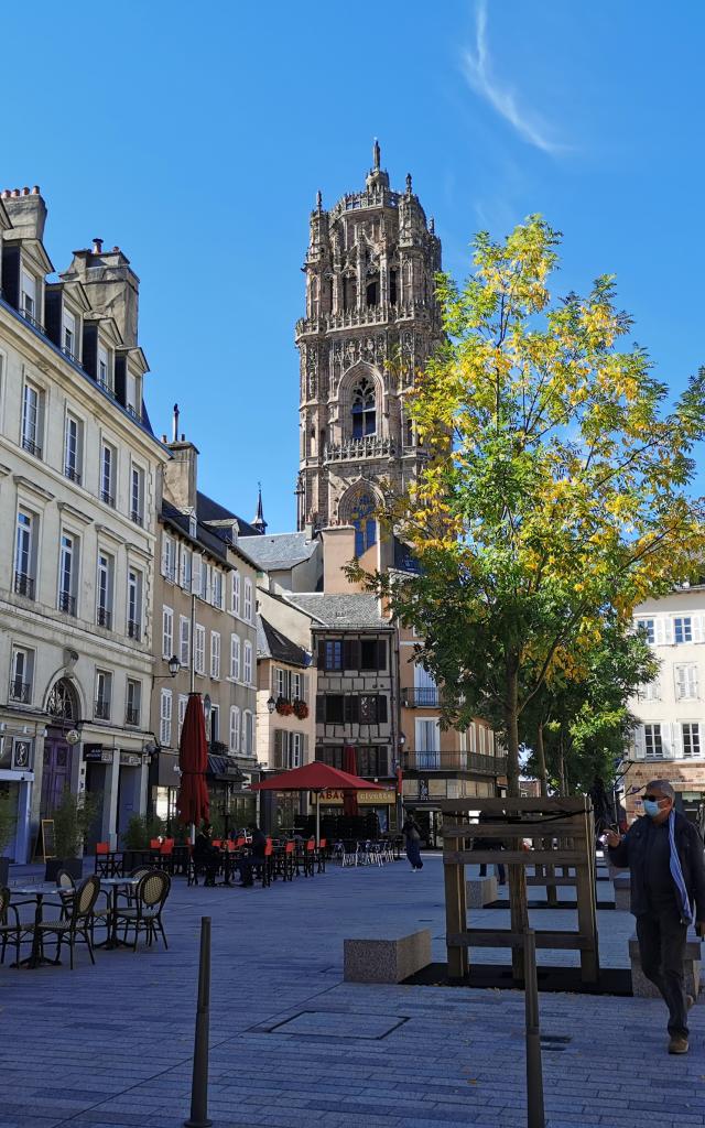 Clocher de la cathédrale vu depuis la place de la Cité et ses terrasses, avec des personnes s'y promenant