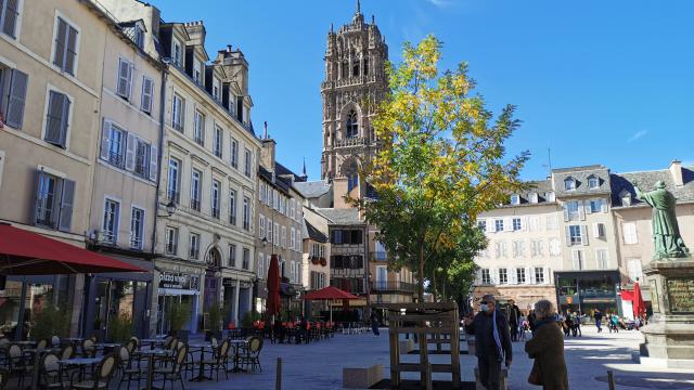 Clocher de la cathédrale vu depuis la place de la Cité et ses terrasses, avec des personnes s'y promenant