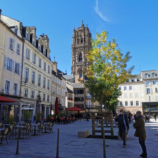 Clocher de la cathédrale vu depuis la place de la Cité et ses terrasses, avec des personnes s'y promenant