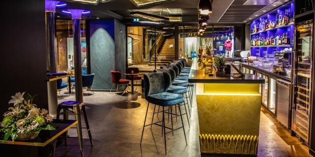 Ambiance feutrée au Bar à cocktails le 16.45, avec son comptoir et ses chaises hautes en velours gris