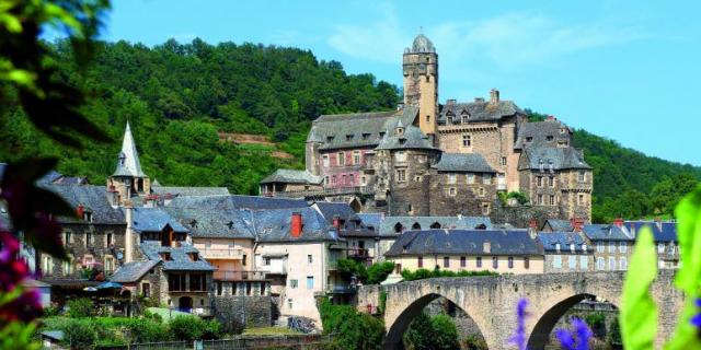 Village d'Estaing avec son châteaux aux fenêtres à meneaux, ses maisons et son pont enjambant la rivière du Lot