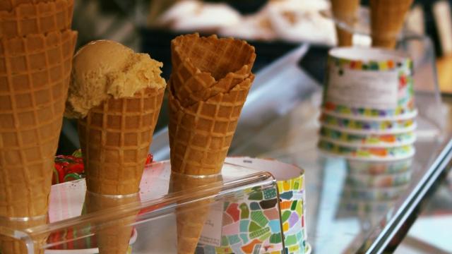 Glaces dans un cornet en biscuit sur un socle en plastique transparent, à côté de pots en carton vides retournés