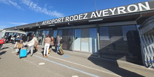 Personnes avec leur valise à roulette et leur sac à dos à l'aéroport Rodez Aveyron