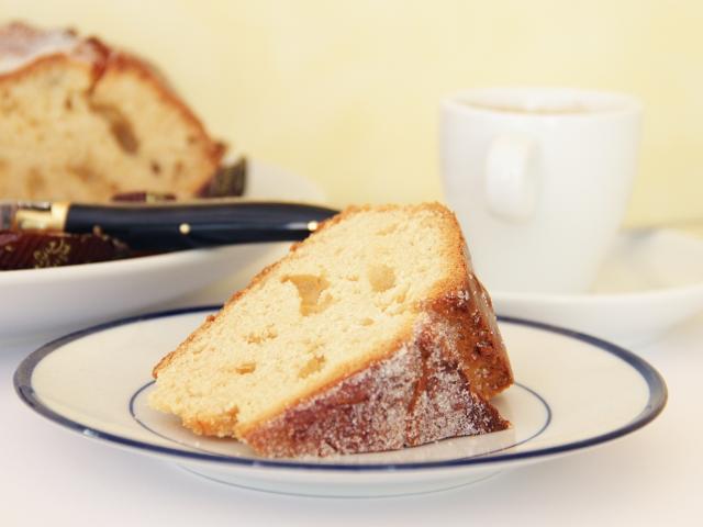 Part de fouace sucrée couchée sur une petite assiette en porcelaine à côté d'une tasse à café