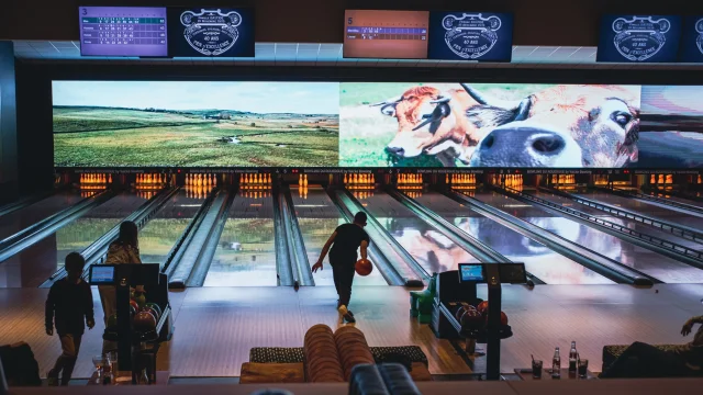 Personne lançant une boule de bowling sur la piste, vers les quilles