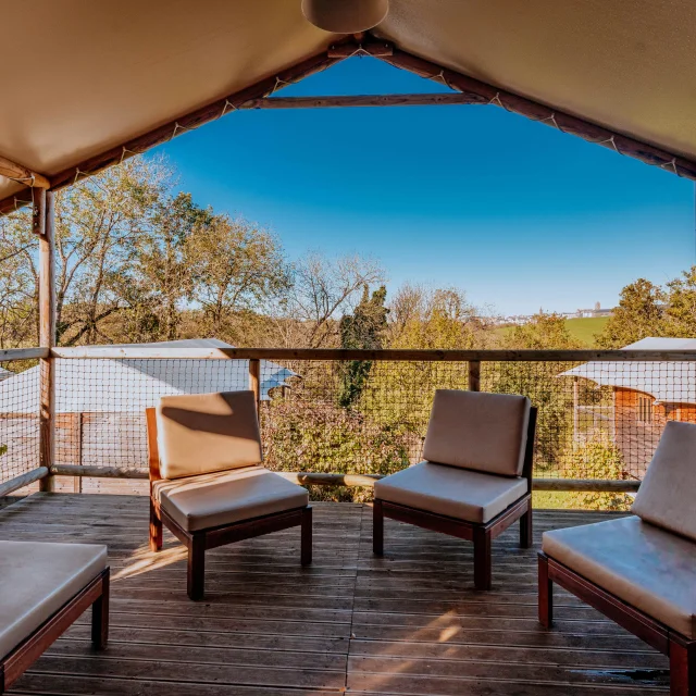 Terrasse d'un chalet avec des fauteuils au Domaine de Combelles, avec vue sur la cathédrale de Rodez